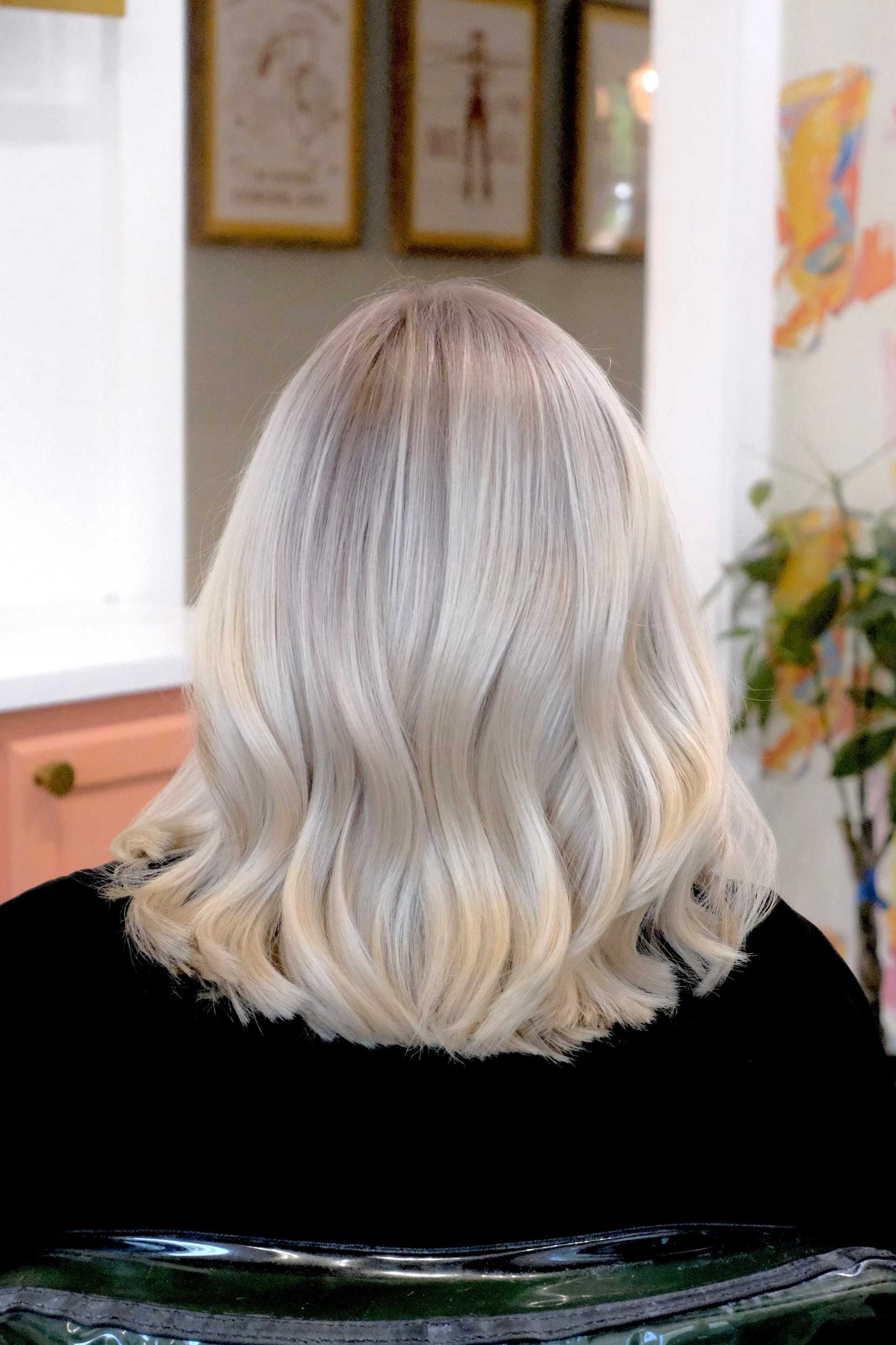 Blonde hair styled in loose waves viewed from the back in a salon setting.